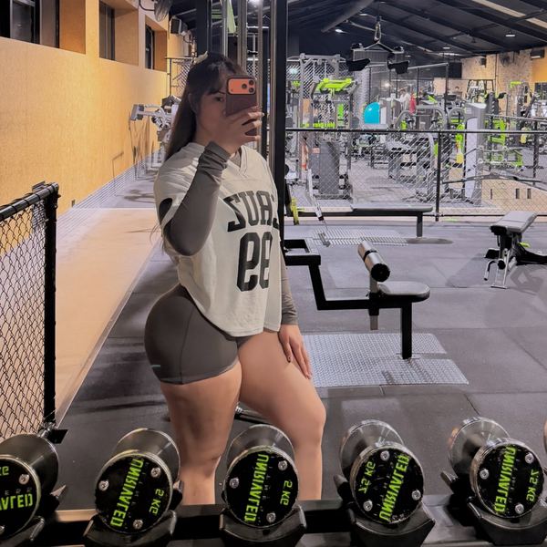 Rachel on a gym floor lined with dumbbells