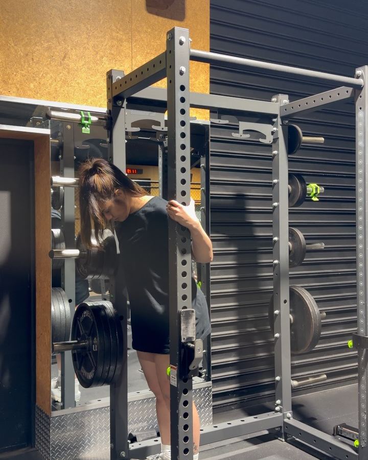 Rachel resting between sets beside a power rack