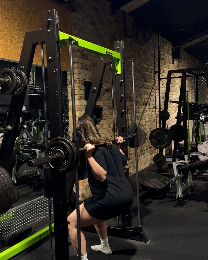 Rachel doing barbell split squats in a squat rack